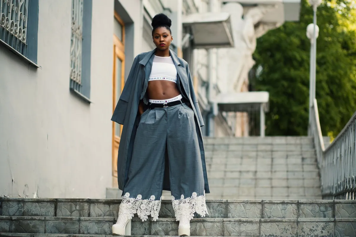 Silhouette féminine en tenue oversize devant un miroir, lignes et volumes visibles