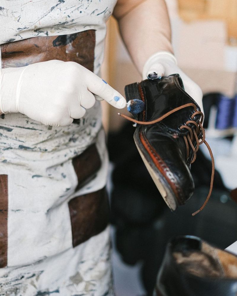 Mains gantées appliquant une crème sur une chaussure en cuir noir
